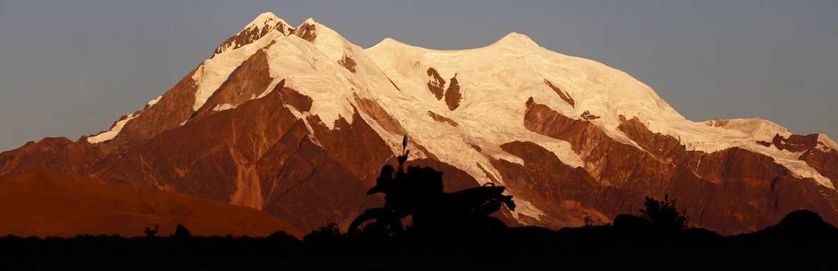 Motorcycle silhouette — Illimani glacier at golden hour